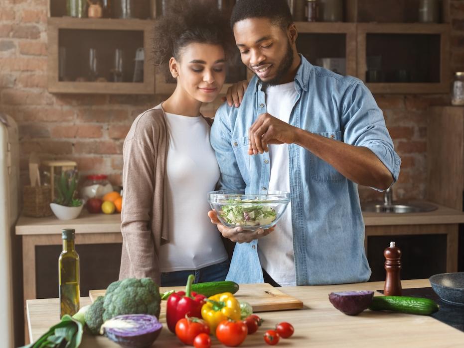 Black man and woman in a kitchen making a salad, tuscaloosa al