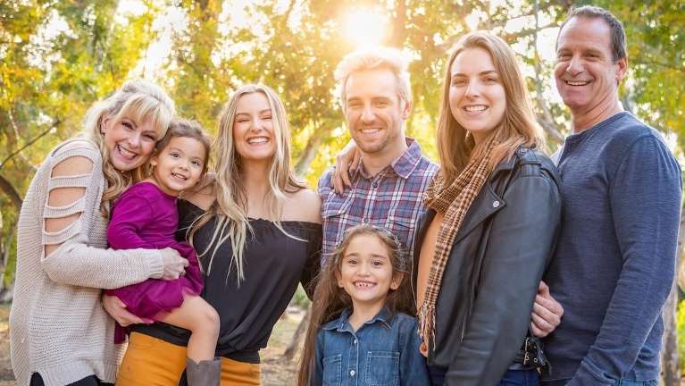 family stands together in bright sunlight, smiling for a photo that reflects their love and unity.