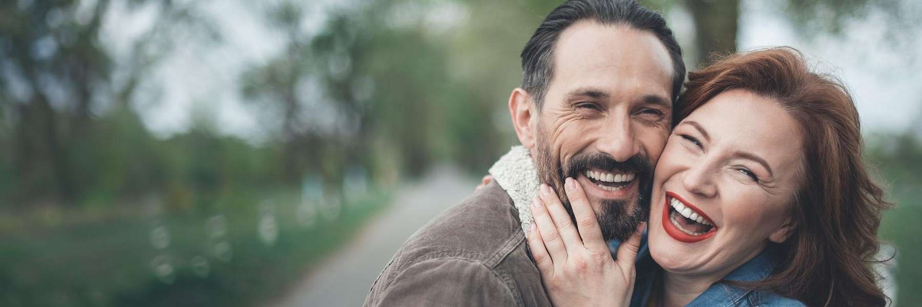 A man and woman share a warm hug, representing the positive outcomes of full mouth rehabilitation